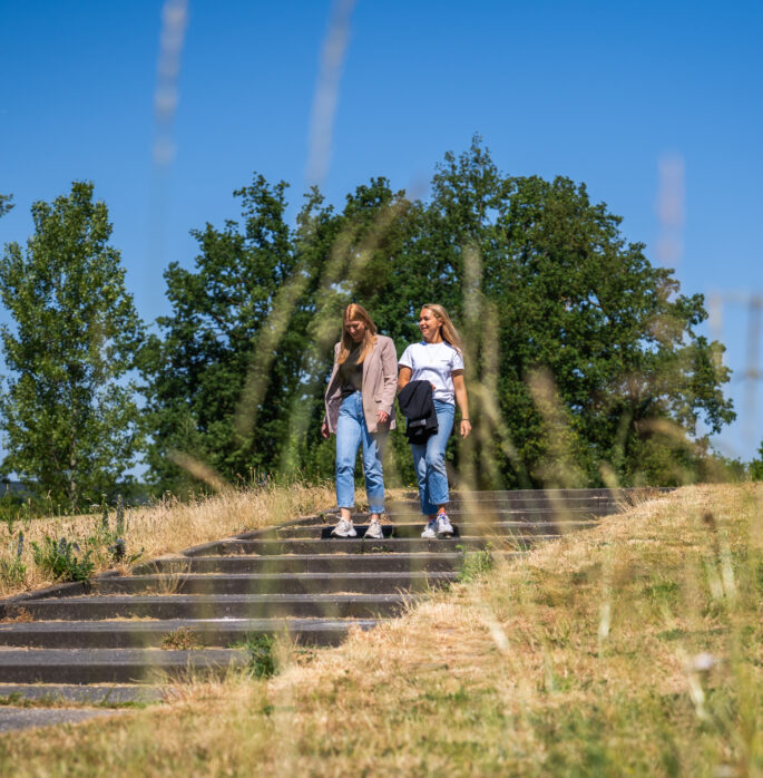 foto van twee vrouwen die door een park wandelen in de zon
