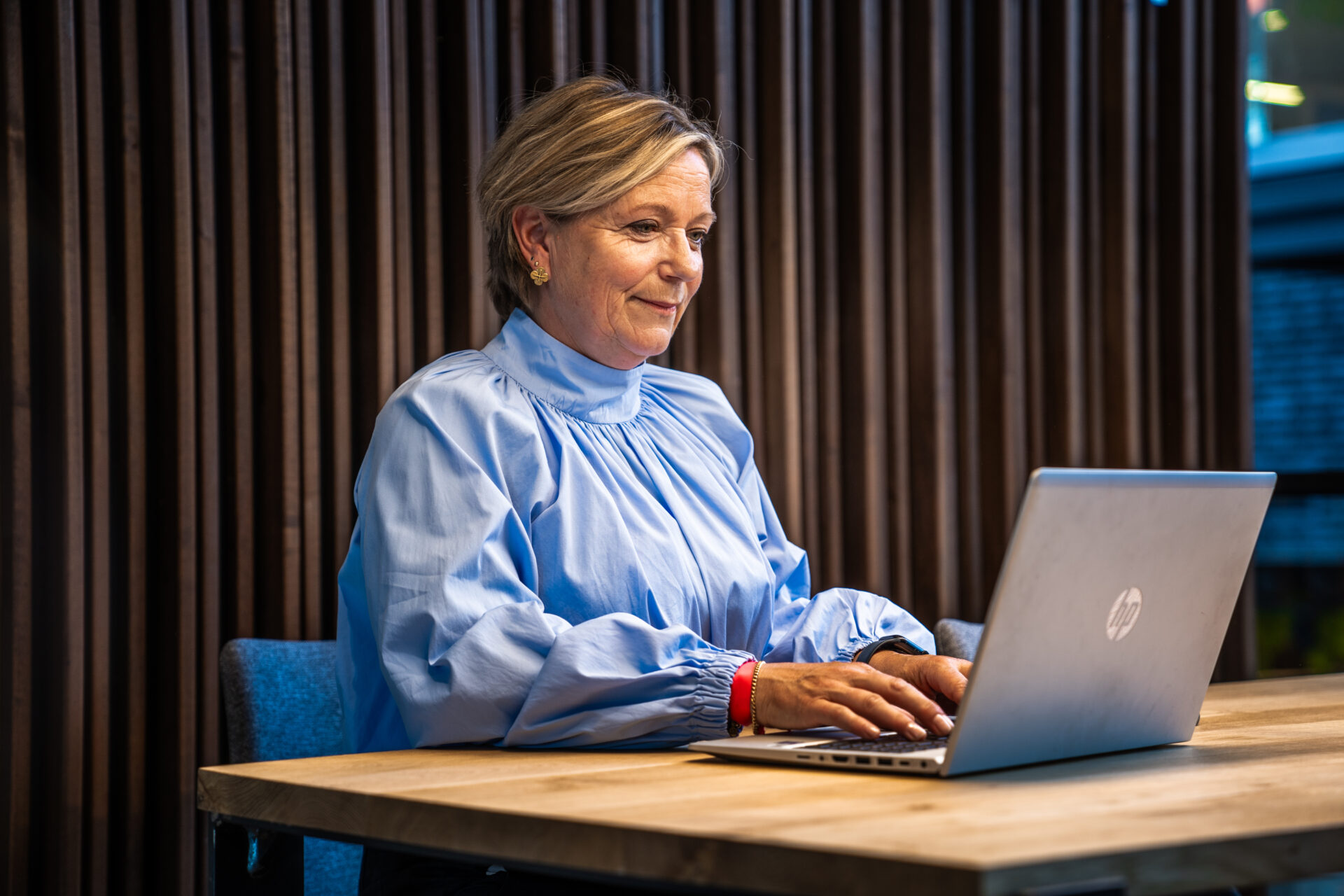 afbeelding van een vrouw die aan tafel zit achter een laptop.