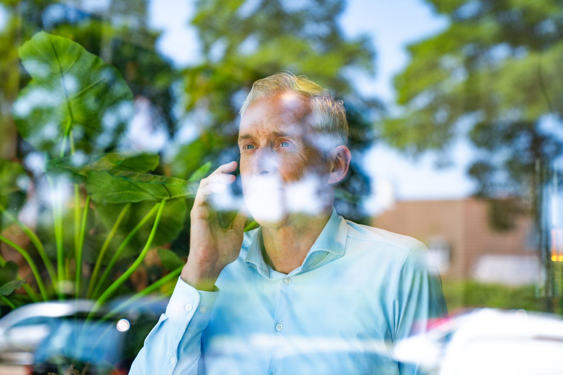 Man telefonerend terwijl hij naar buiten kijkt.