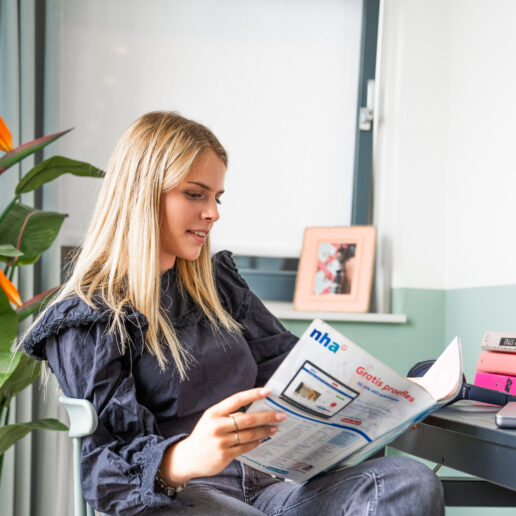 afbeelding van jonge meid die een tijdschrift leest achter een bureau.