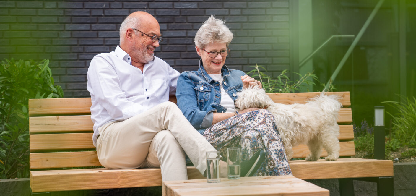 afbeelding van volwassen man en vrouw op houten bankje met hond.