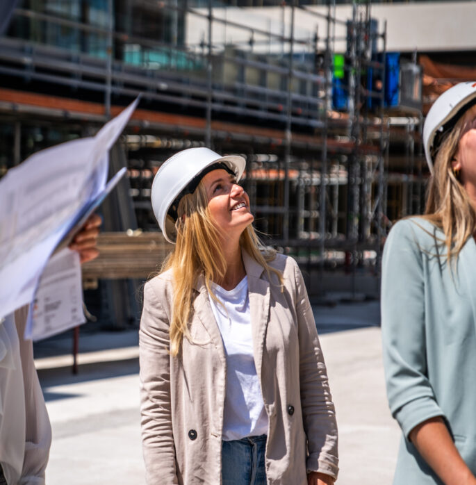 Collega op bouwplaats lachend naar boven kijkend