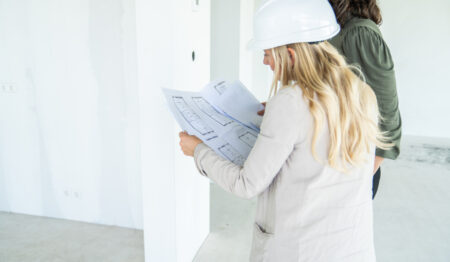 twee vrouwen op de bouw met bouwhelm op en bouwtekening in hun hand