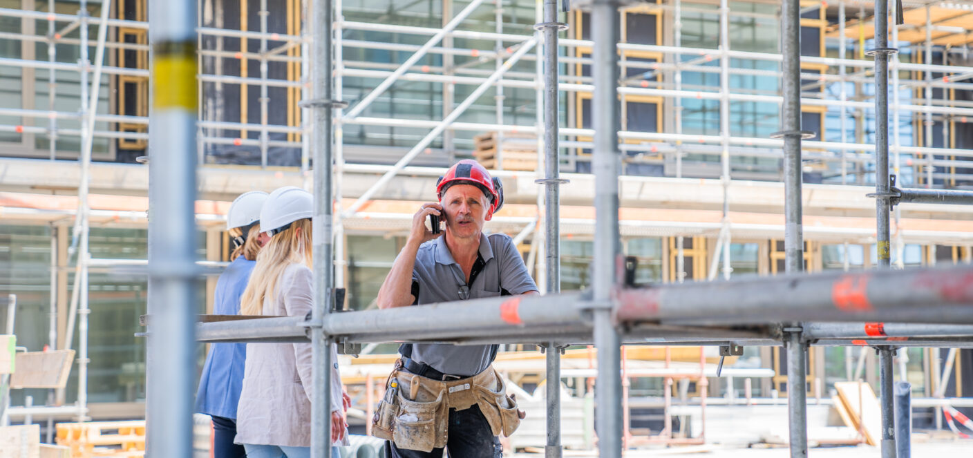 Afbeelding van een bouwvakker op de bouw die aan het bellen is.