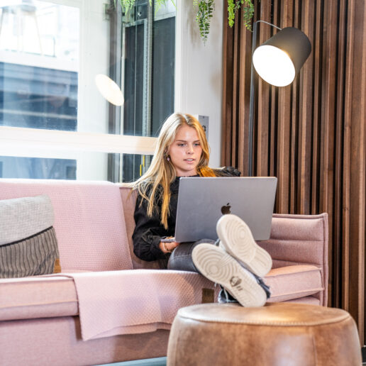 Student zittend op bank met laptop op schoot