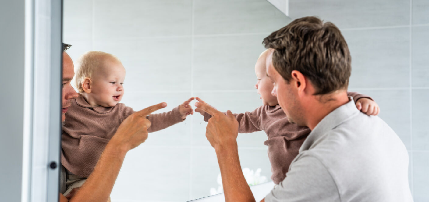 Jonge vader met baby voor de spiegel.