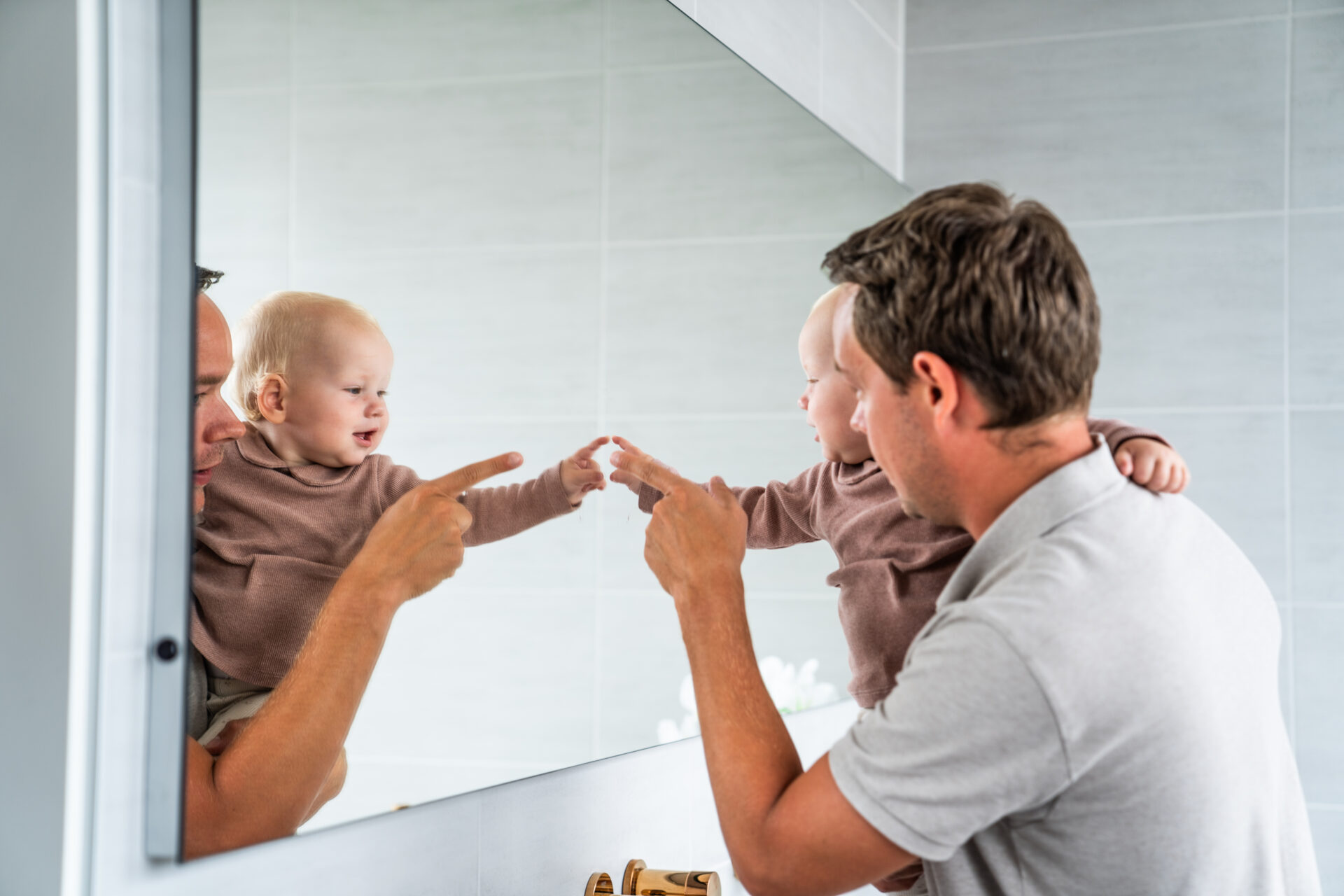 Jonge vader met baby voor de spiegel.