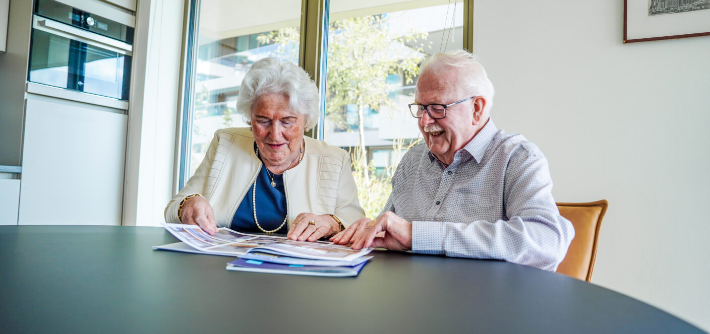 Twee senioren zitten samen thuis en bespreken hun woonsituatie en toekomst