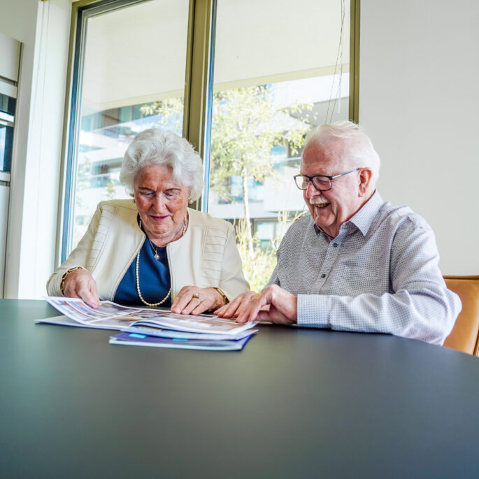 Twee senioren zitten samen thuis en bespreken hun woonsituatie en toekomst
